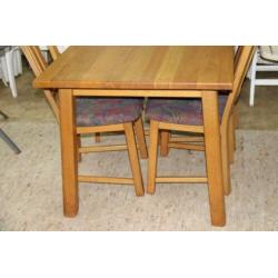 Lichte eiken eettafel met 4 stoelen met stoffen bekleding.