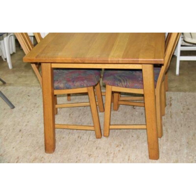 Lichte eiken eettafel met 4 stoelen met stoffen bekleding.