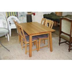 Lichte eiken eettafel met 4 stoelen met stoffen bekleding.
